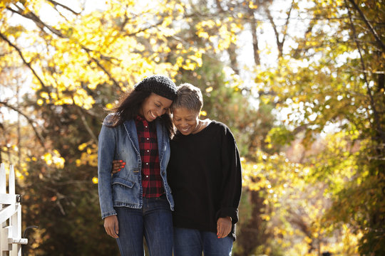 Mother and daughter holding each other walking against background of autumn foliage