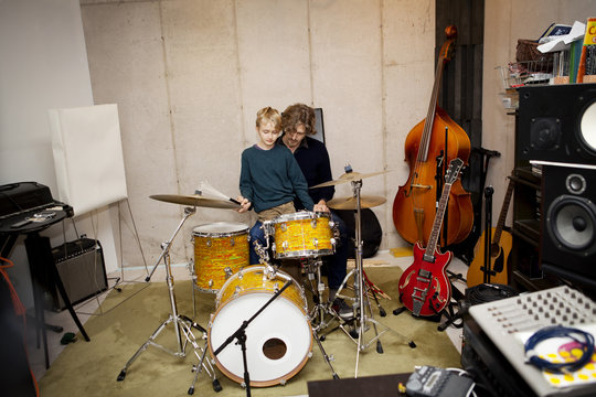 Father teaching son ( 8-9 ) playing drums