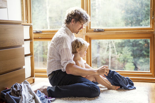 Father changing son's (18-23 months) clothes in domestic room