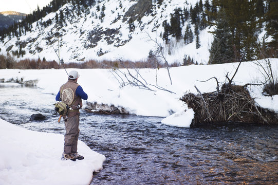 Man fly-fishing on mountain river in winter