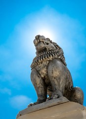 Brave Lion Posture sitting Statue on a mountain view top cliff with sun shine on top blue sky and...