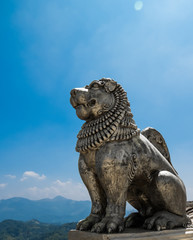 Brave Lion Posture sitting Statue on a mountain view top cliff with blue sky and clouds at Nelligala International Buddhist Center Kandy, Sri Lanka