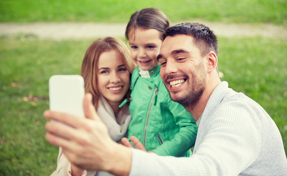 happy family taking selfie by smartphone outdoors