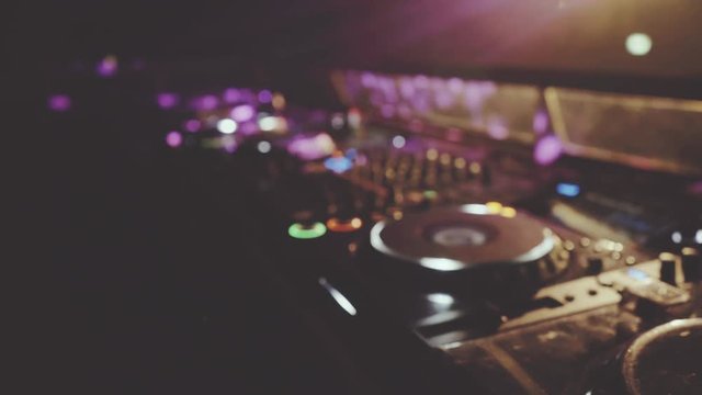 behind dj decks and mixer in night club, focus pull