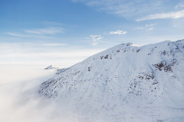 Fototapeta na wymiar Low clouds envelops the snowy mountain peak in the Tatras.