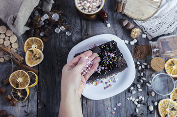 Female hand sprinkles sugar hearts piece of