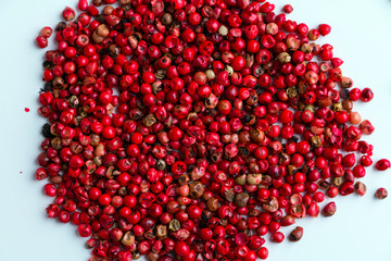 Pink peppercorns pile on white desk. Closeup. Top view. Round.