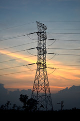 Electricity transmission pylon silhouetted against sunset sky