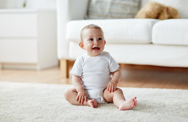 happy baby boy or girl sitting on floor at home