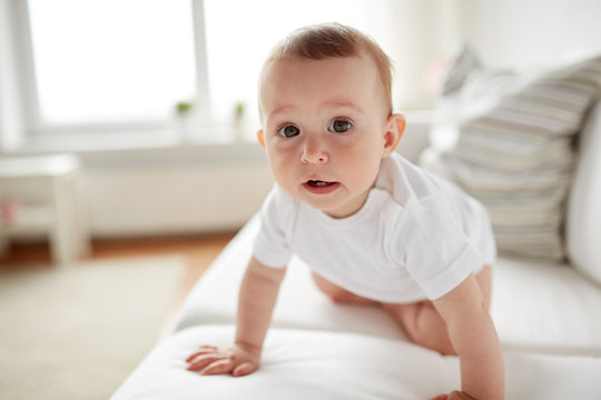 little baby in diaper crawling along sofa at home