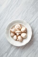 Mushrooms on a plate on a marble background. Top view