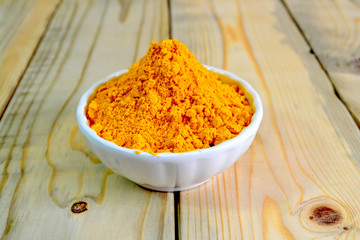 Tumeric powder in a bowl isolate on wooden background