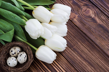 Bouquet white  tulip flowers with  easter eggs on wooden table. Place for your text. Easter background.