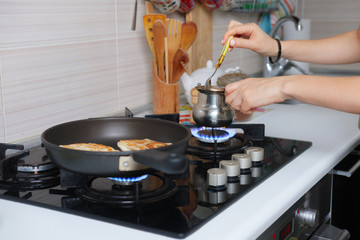 Nobody making pancakes in pan and coffee in pot for breakfast on stove in home kitchen