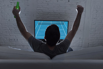 back view with young man home alone watching Grand slam tennis match in television on sofa