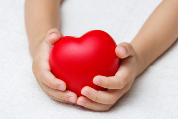 Red heart in baby palm hands