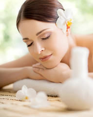 Young and beautiful girl relaxing in spa salon. Massage therapy over seasonal summer or spring background. Healing medicine and health care concept.