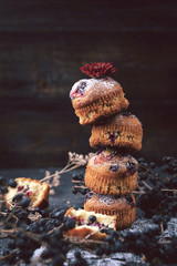 muffin with currants on a dark background next to the berries on the branches. and a bouquet of flowers. in a rustic style. dark style