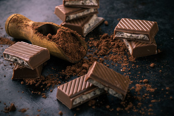 Cocoa in wooden spoon on dark tray with chocolate_