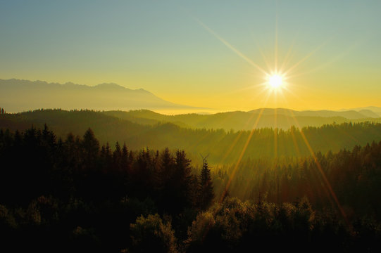 Summer High Tatras mountain landscape. Sunrise at monumental hills. Golden colored forest and peaks. Fog and inversion
