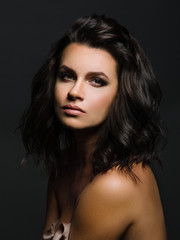 Naklejka premium Portrait of young woman on dark background. Brunette with brown eyes.