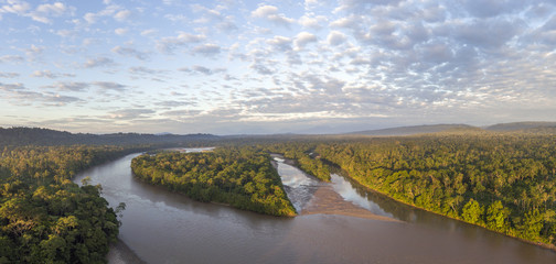 Aerial view of the Rio Napo at dawn in the Ecuadorian Amazon with the first rays of the sun illuminating the forest canopy.