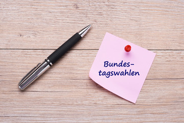 Bundestagswahl als Wort auf rosa Haftnotiz mit rotem Pin