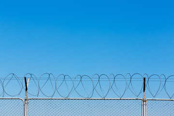 Barbed wire fence on blue sky