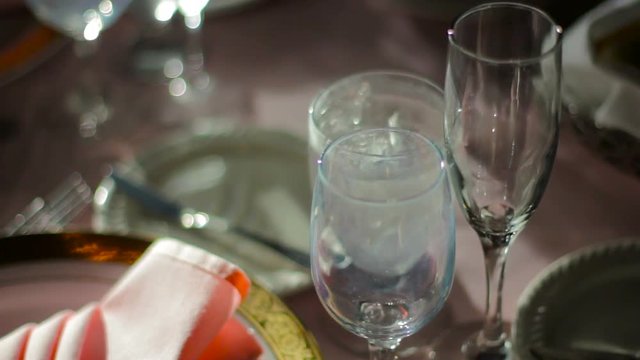 Spotlight on a set table as the camera tilts up to the glasses.