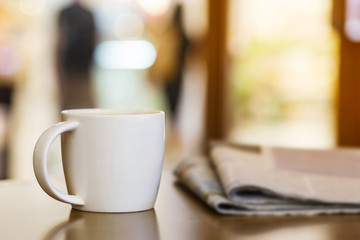 Cappuccino coffee cup on wooden table with newspaper