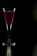 Glass with red liquor on a black background