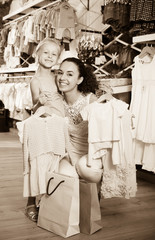 Fototapeta premium Happy woman with small child holding clothes