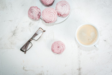 Home spring vacation, relax, work. White stone concrete desk with coffee and pink berry cakes (Marshmallow), top view, copy space