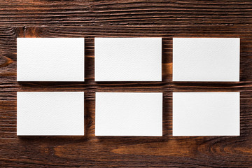 Closeup mockup of six white horizontal business cards at brown wooden table background.