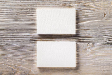 Closeup mockup of two blank horizontal business cards at light natural wooden background.