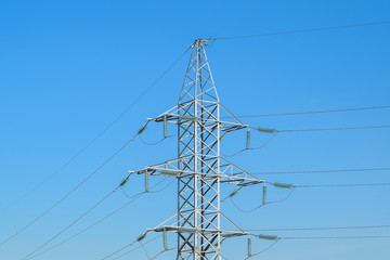 Supports high-voltage power lines against the blue sky