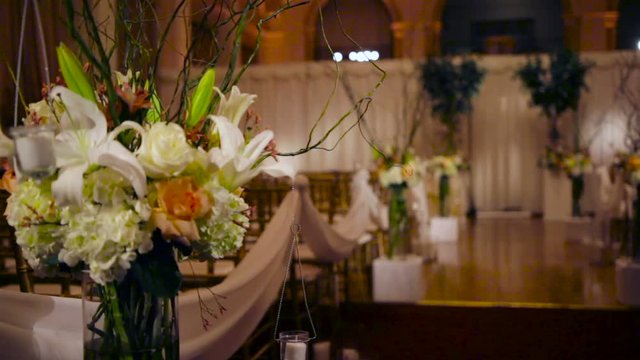 Classy and elegant wedding ceremony setup indoors with rows of empty chairs and gorgeous flower arrangements.