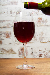 Glass of full bodied red wine being poured