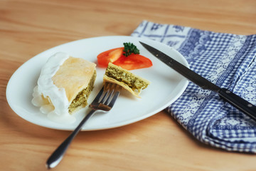 pie with spinach and tomato slice on wooden table.