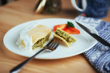 pie with spinach and tomato slice on wooden table.