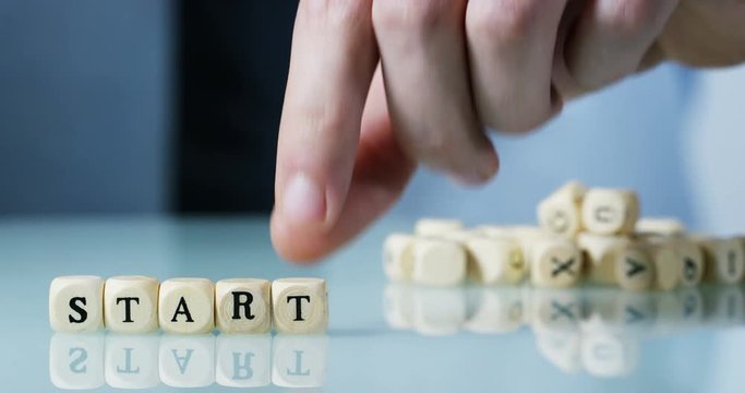 Young businessman hand creates the word "Start" of the wooden letter blocks . Concept of financial market and future of stock market business.