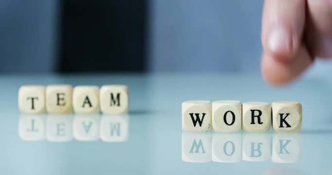 Young businessman hand creates the word "Team work" of the wooden letter blocks . Concept of financial market and future of stock market business.