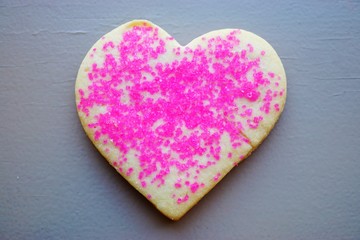 A heart shaped sugar cookie with red and pink sprinkles for Valentine's Day