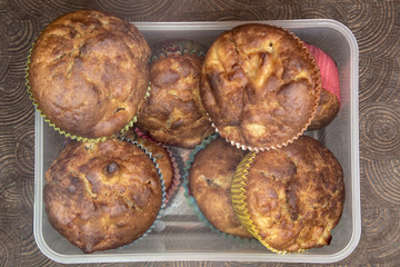 Fresh hand made muffins in transparent box on dark wooden background