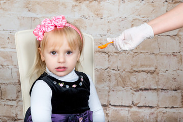 Doctor hand giving spoon dose of medicine liquid drinking syrup to child
