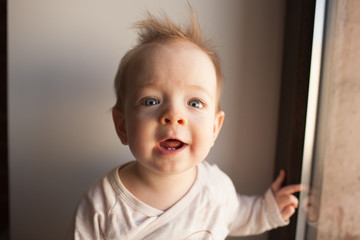 Portrait of a little boy who is sitting at the window and wonders. emotions concept