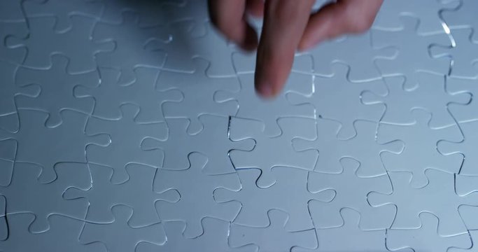 A creative completes the black or white light puzzle putting the last missing piece. Concept: cooperation, teamwork, creativity, and access solution.