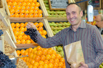 Man holding bunch of grapes in store