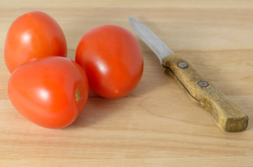 Tomatoes on the cutting board and a knife.