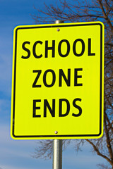 Close Up of School Zone Ends Sign Against Sky Background With Tree